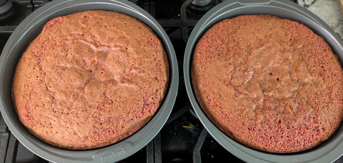 Two baked red velvet cake rounds in their pans.
